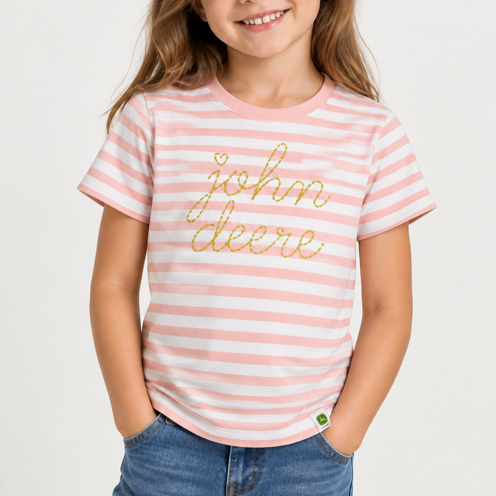 A young girl wearing a pink and white striped t-shirt with 'john deere' written in gold glitter script across the chest, paired with blue jeans, against a clean white background.