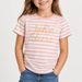 A young girl wearing a pink and white striped t-shirt with 'john deere' written in gold glitter script across the chest, paired with blue jeans, against a clean white background.