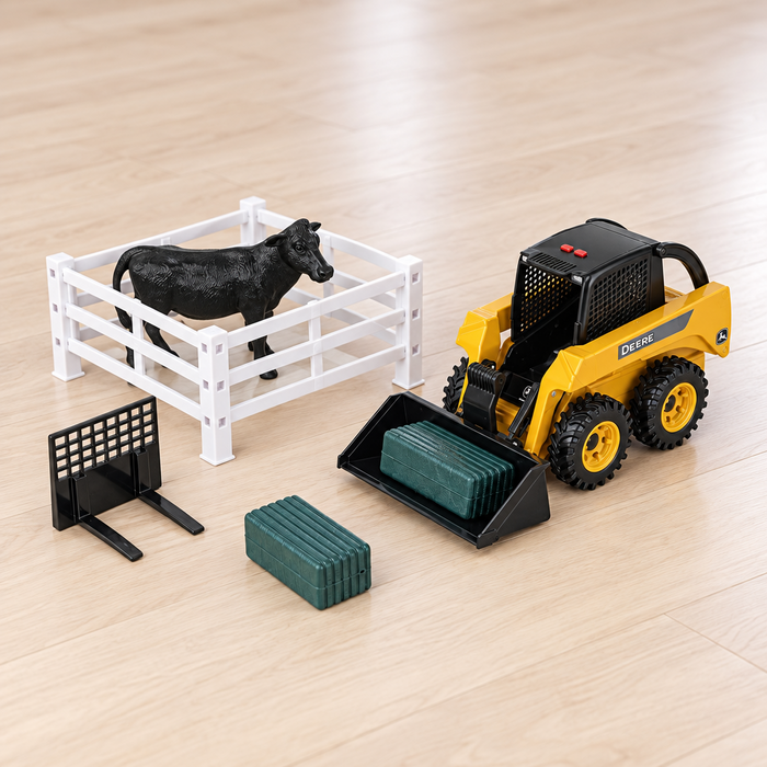A John Deere 1:16 Big Farm Skid Steer Set on a light wood floor, featuring a yellow and black toy skid steer, a white plastic pen with a black cow figure, a black gate, and green blocks.