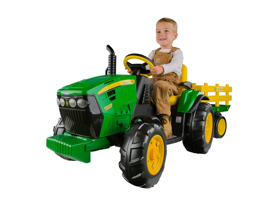 a child sits on top of the John Deere 12 Volt Ground Force Tractor with Trailer