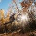 Person on a Vamoose Matador FS Downhill E-Bike in mid-air against a sunlit forest background